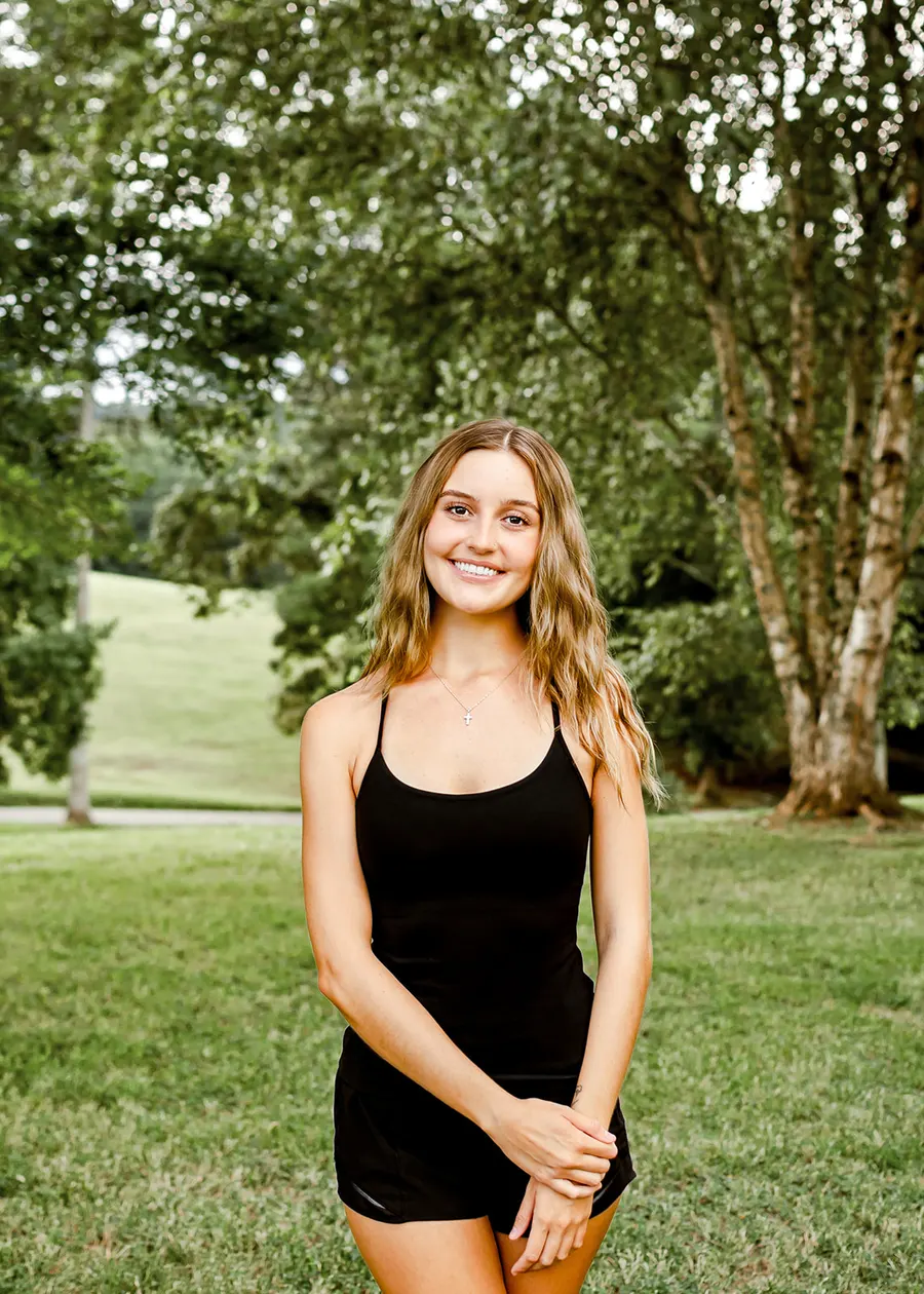 Avery standing in the park under the trees