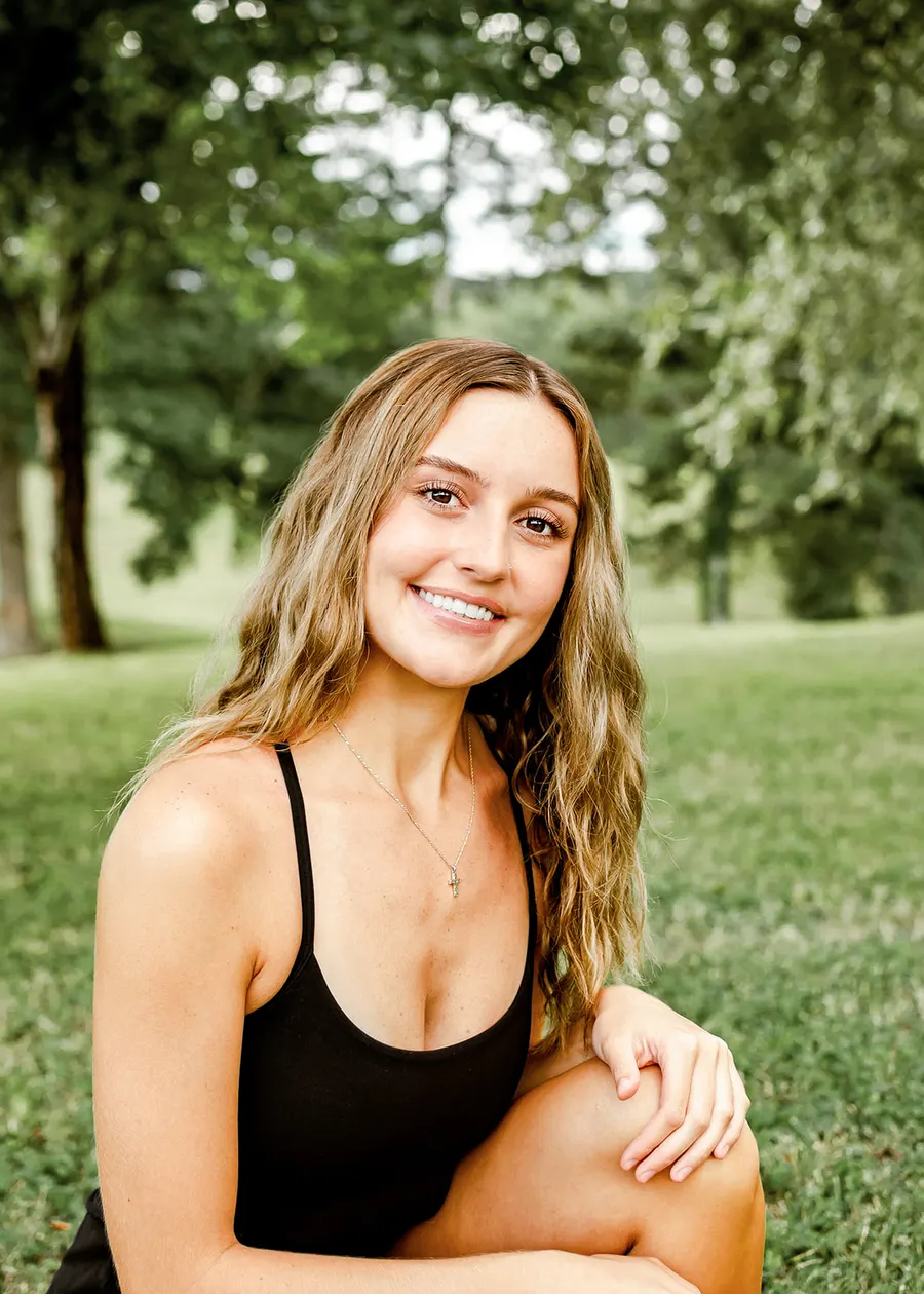 Avery kneeling in the grass, smiling