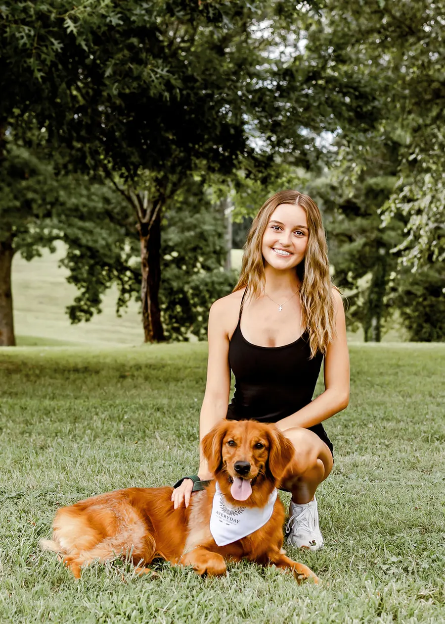 Avery kneeling behind the golden lying in the grass